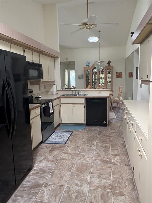 A kitchen with beige cabinets, black appliances, and tile flooring opens to a dining area — 22 BRISTOL DRIVE, PALM COAST, FL