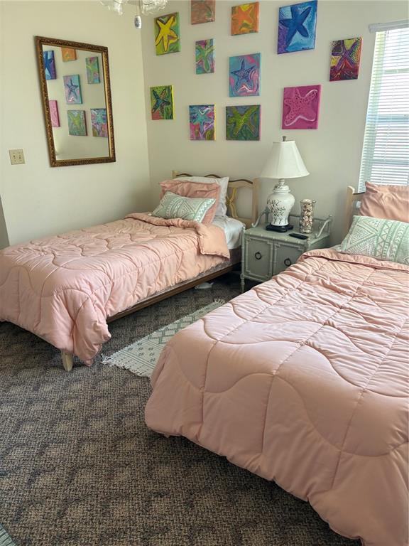A bedroom features two twin beds with pink bedding, a nightstand, and starfish wall art — 22 BRISTOL DRIVE, PALM COAST, FL