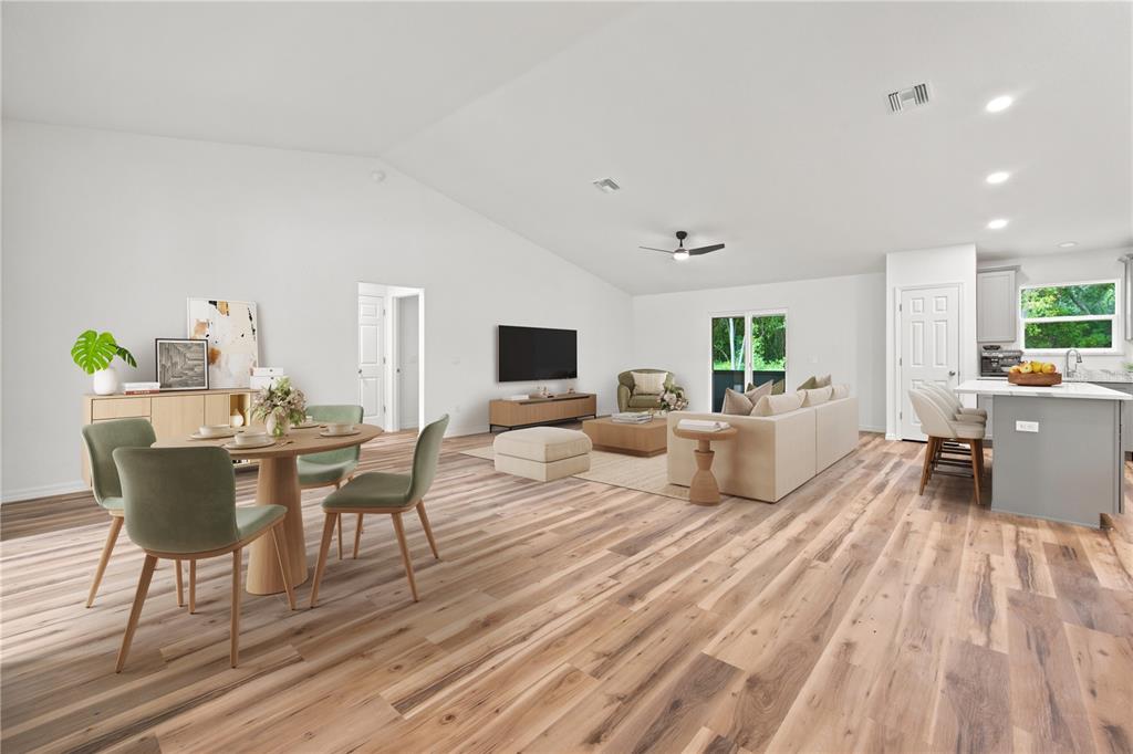 This open-concept living and dining area features light wood flooring and a vaulted ceiling — 7784 SW 146TH LANE ROAD, OCALA, FL