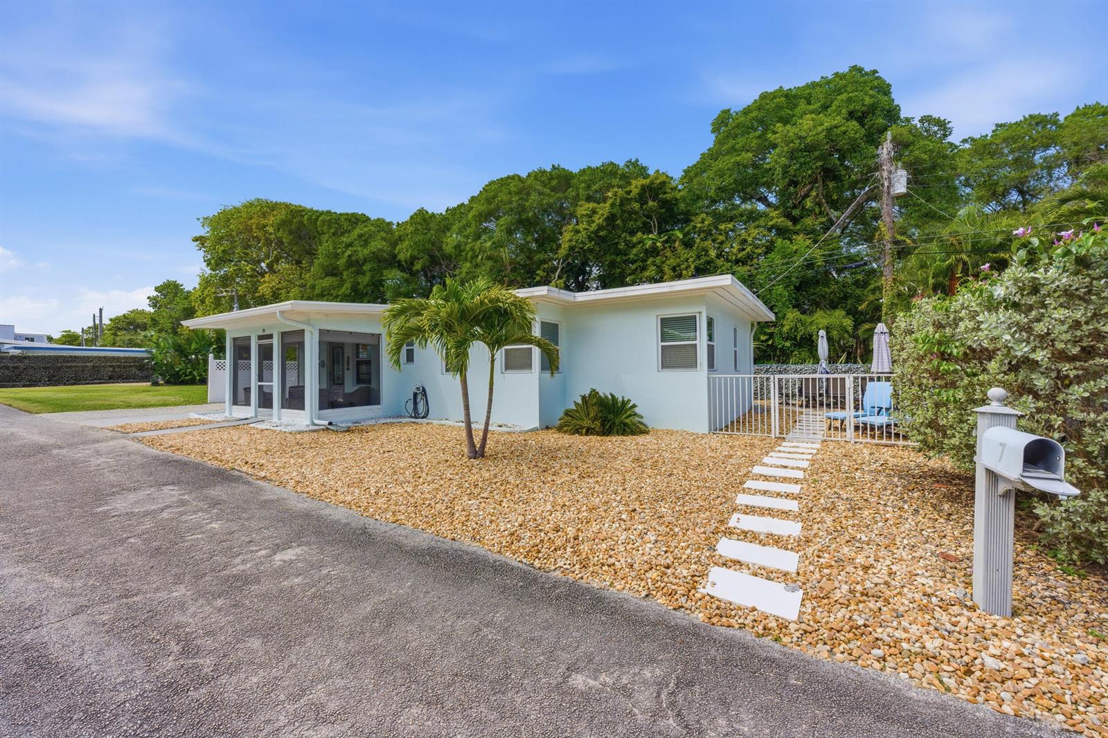 A light blue single-story house features a screened-in porch, gravel yard, and white fence — 7 Belair Drive, Boynton Beach FL 33435, BOYNTON BEACH, FL