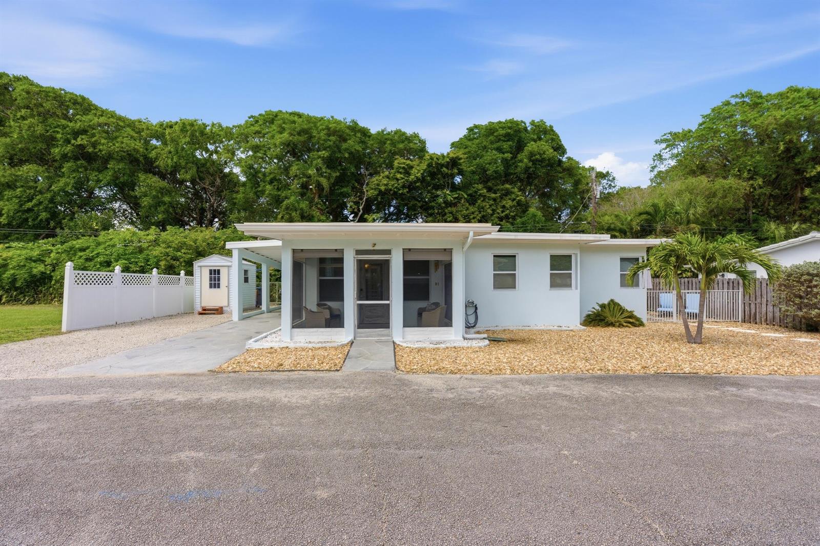 A light blue single-story house features a screened front porch, a carport, and gravel landscaping — 7 Belair Drive, Boynton Beach FL 33435, BOYNTON BEACH, FL
