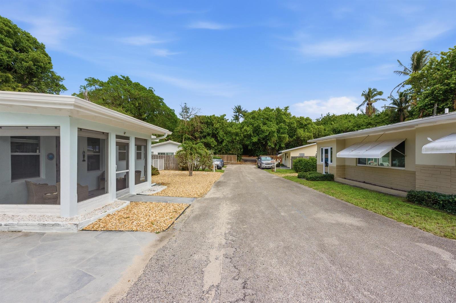 A paved driveway runs between two single-story residential buildings with light-colored siding and landscaping — 7 Belair Drive, Boynton Beach FL 33435, BOYNTON BEACH, FL