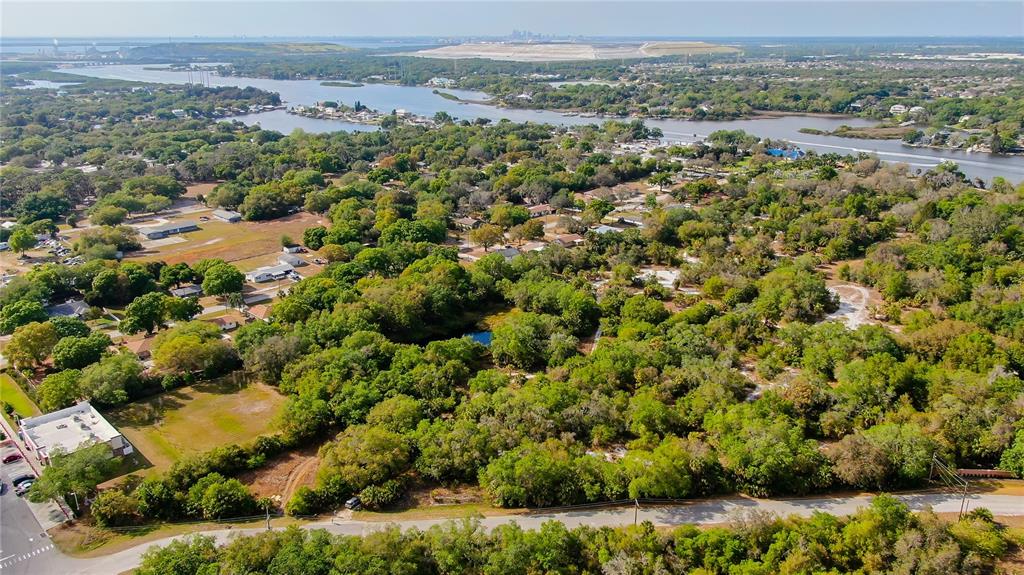 An aerial view shows a wooded lot with a small pond near a waterfront area — 9236-9248,9234 OLD GIBSONTON DRIVE, GIBSONTON, FL