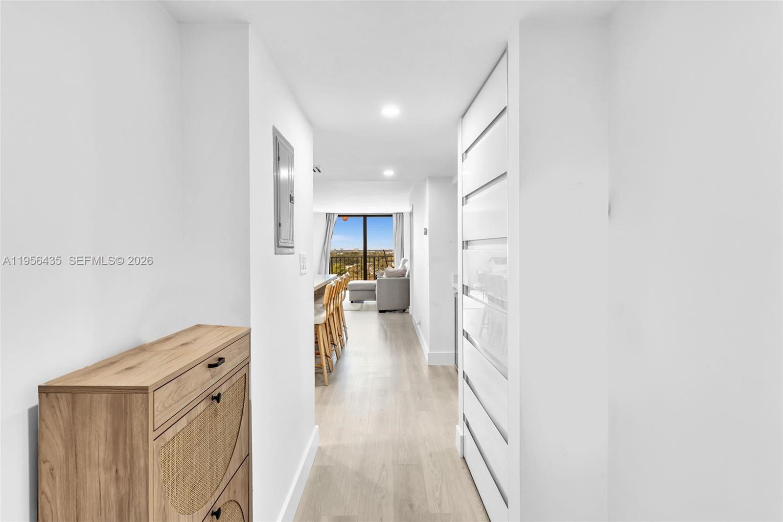 A hallway with light wood flooring leads to an open-concept living area with balcony views — 2625 Collins Ave # 1109, Miami Beach FL 33140, MIAMI BEACH, FL