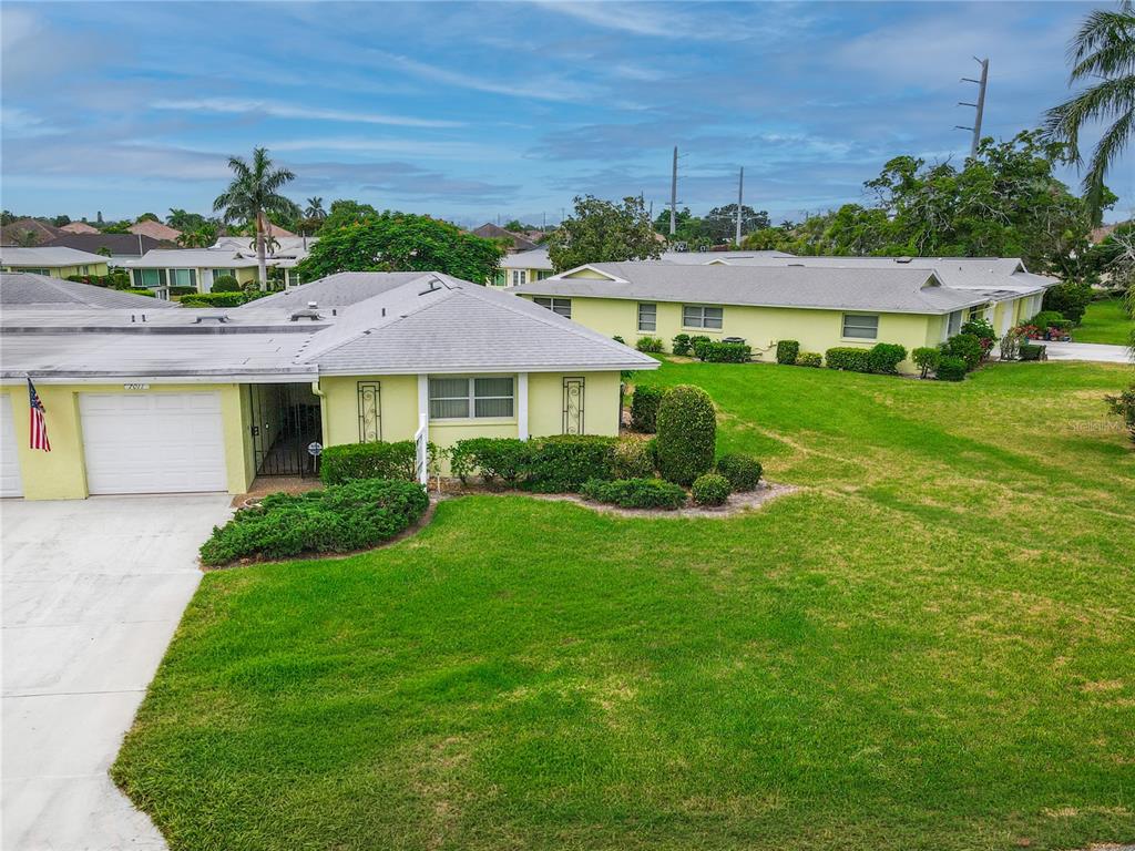 An aerial view of a single-story yellow house with a white garage and lawn — 7011 10TH AVENUE W, BRADENTON, FL