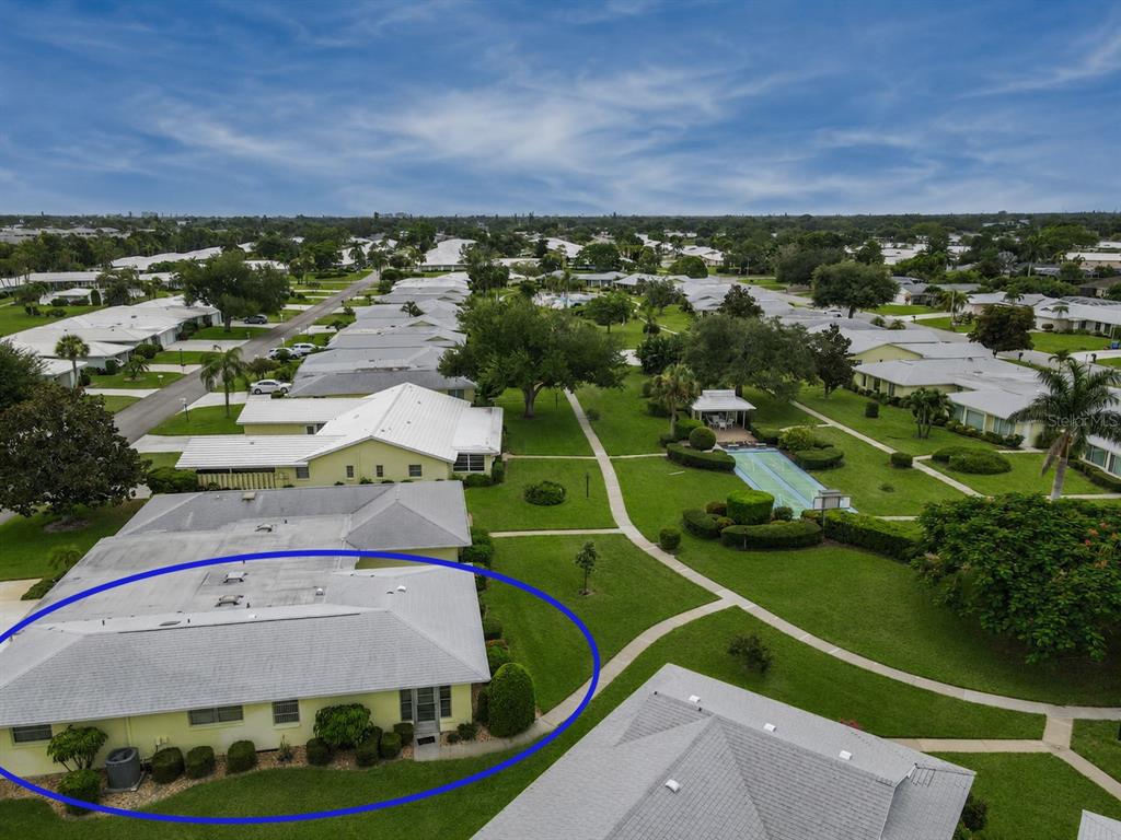 An aerial view shows a light yellow, single-story residential building with a gray roof — 7011 10TH AVENUE W, BRADENTON, FL