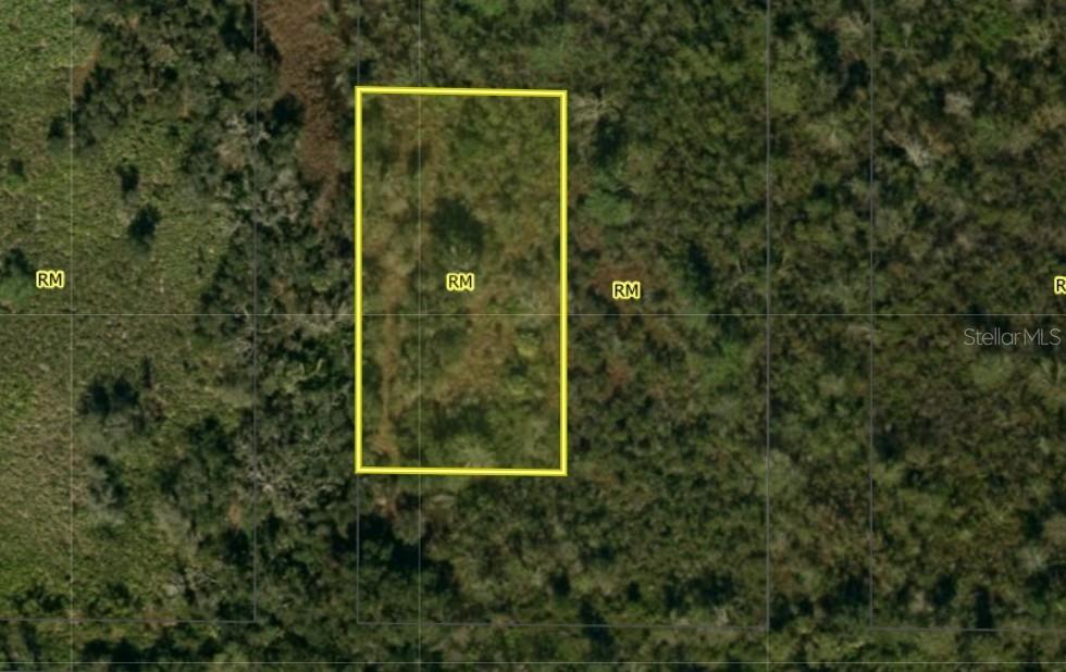 An aerial view shows a rectangular plot of land outlined in yellow amidst wooded terrain — SW PABLO AVENUE, ARCADIA, FL