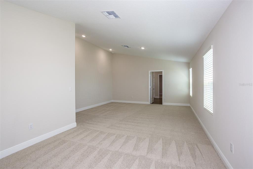 An empty room features beige carpet, light-colored walls, recessed lighting, and two windows — 9859 GOVREAU ROAD, WESLEY CHAPEL, FL