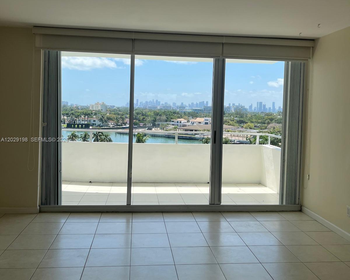 A room with light tile flooring features a large sliding glass door leading to a balcony — 5161 Collins Ave # 909, Miami Beach FL 33140, MIAMI BEACH, FL