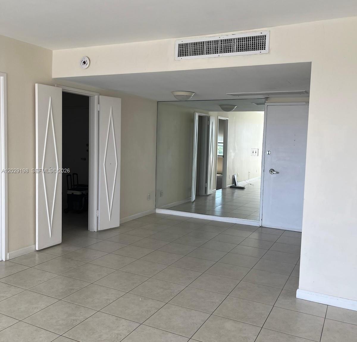 A room with tiled flooring, a mirrored wall, and white doors — 5161 Collins Ave # 909, Miami Beach FL 33140, MIAMI BEACH, FL