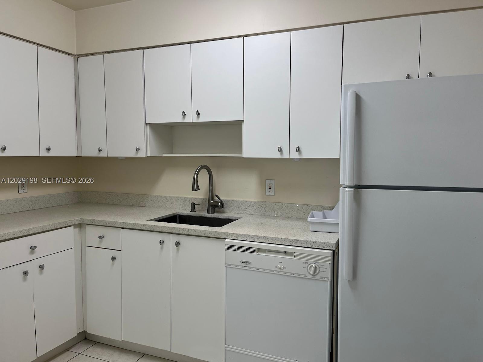 A kitchen features white cabinets, a dark sink, a dishwasher, and a white refrigerator — 5161 Collins Ave # 909, Miami Beach FL 33140, MIAMI BEACH, FL