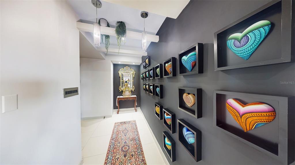A hallway features a dark gray wall decorated with framed heart art and a runner rug — 00690 COND TREASURE POINT UNIT 372, VEGA ALTA, PR