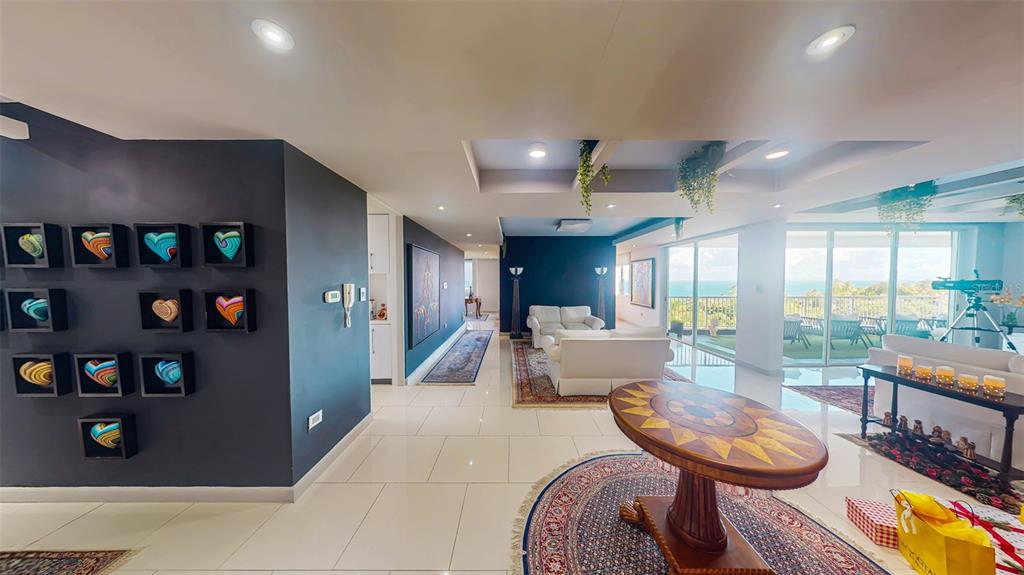 A spacious living area features white tile floors, dark accent walls, and a scenic ocean view — 00690 COND TREASURE POINT UNIT 372, VEGA ALTA, PR