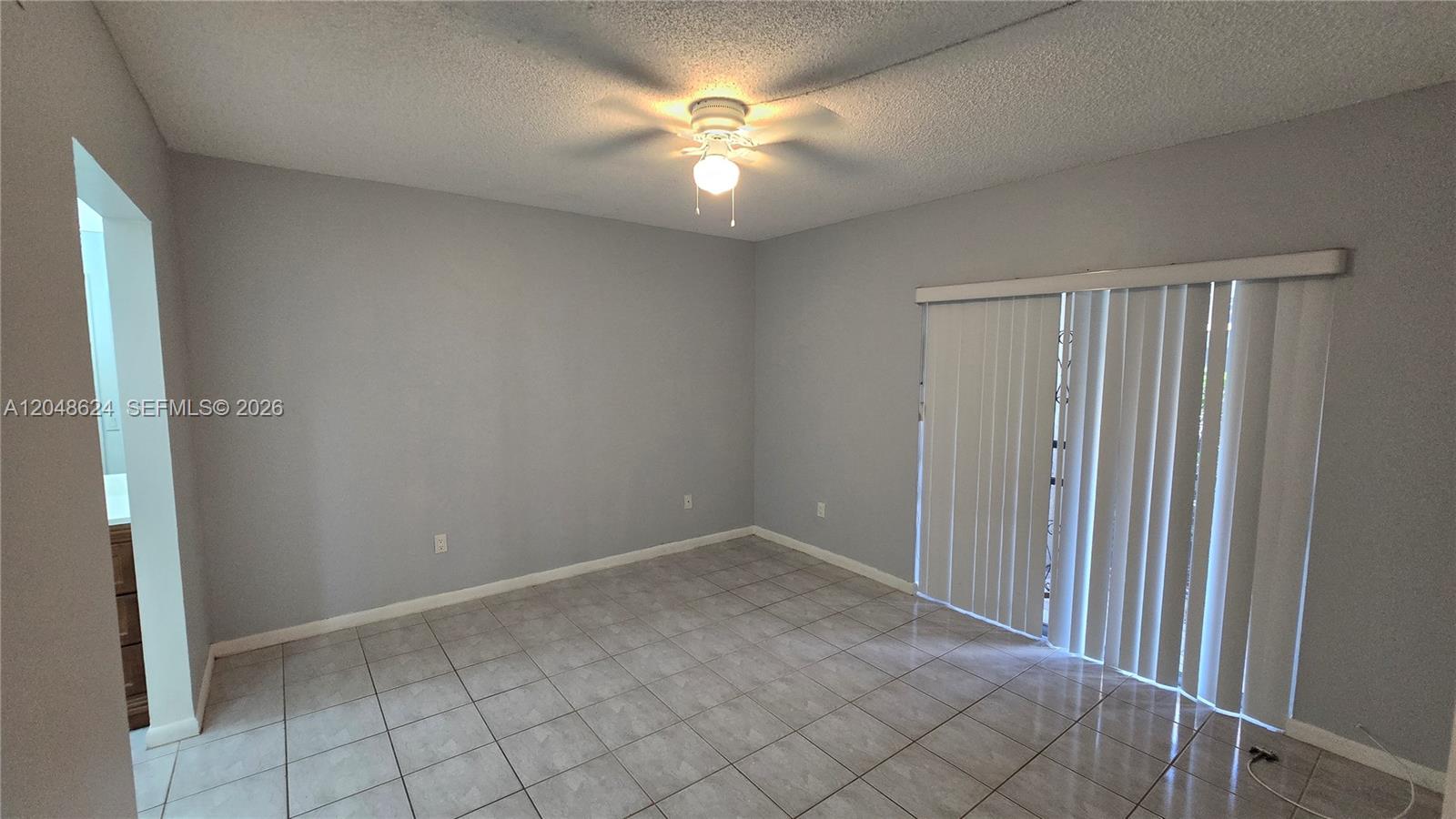 An empty room features light gray walls, tile flooring, a ceiling fan, and sliding glass doors — 8401 SW 107th Ave # 174E, Miami FL 33173, MIAMI, FL