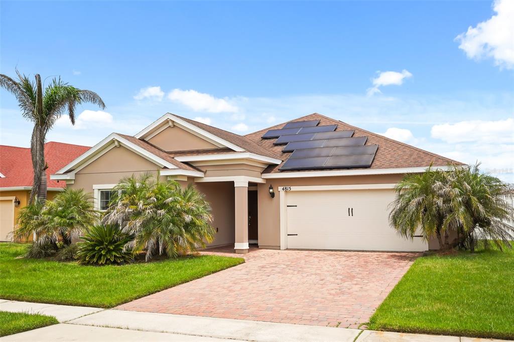 A single-story house with a tan exterior, a brick driveway, and solar panels on the roof — 4815 LAKE SHEPPARD STREET, KISSIMMEE, FL