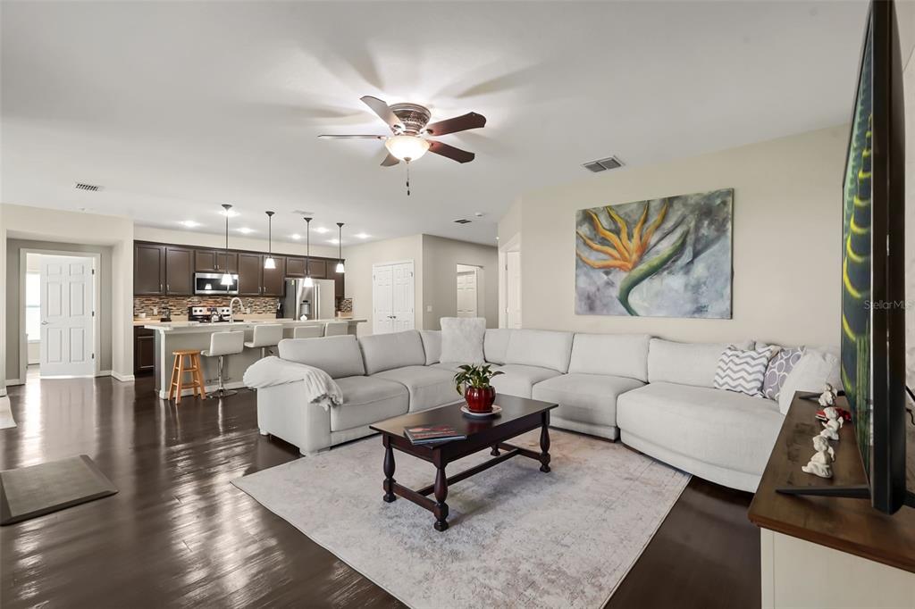 A living room with a large sectional sofa, coffee table, and an open-concept kitchen — 4815 LAKE SHEPPARD STREET, KISSIMMEE, FL