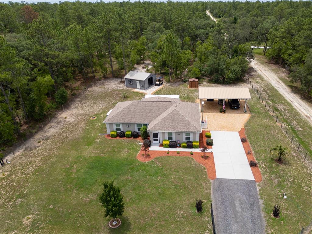 An aerial view shows a single-story house with a carport, detached garage, and wooded surroundings — 12368 SW 81ST STREET, DUNNELLON, FL