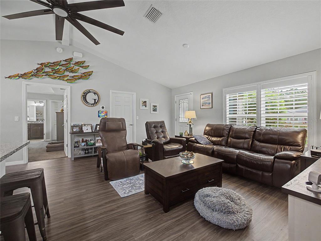 A living room features wood-look flooring, a brown leather sofa, two recliners, and a ceiling fan — 12368 SW 81ST STREET, DUNNELLON, FL
