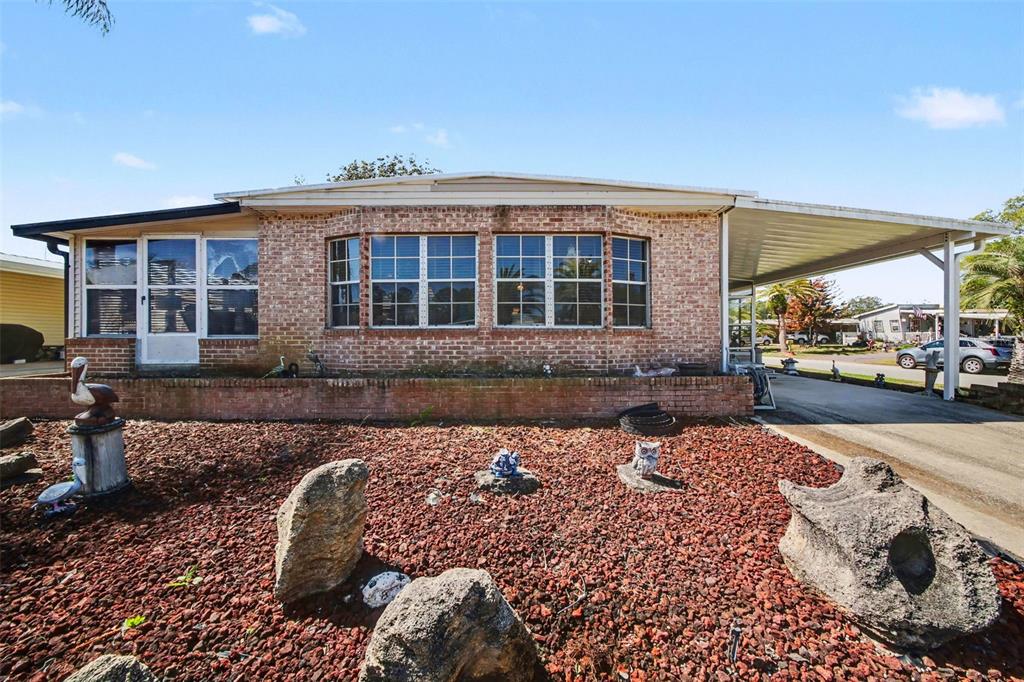 A single-story brick house features a front yard with red gravel and a carport — 732 DOVE AVENUE, PORT ORANGE, FL