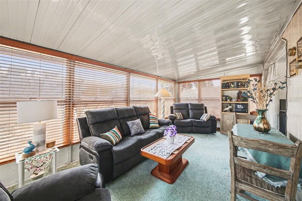 A sunroom features a dark sofa, a coffee table, a dining set, and wood blinds — 732 DOVE AVENUE, PORT ORANGE, FL