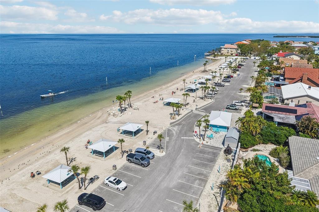 An aerial view shows a sandy beach with picnic shelters, parking, and nearby houses — 3855 TOPSAIL TRAIL, NEW PORT RICHEY, FL