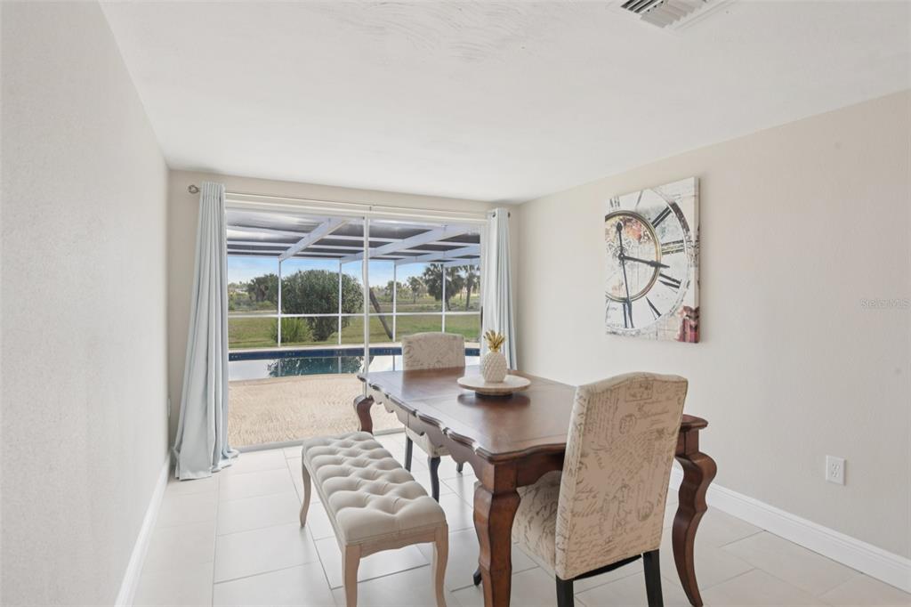 A dining room with tile floors, a wooden table, and a view of a pool — 3855 TOPSAIL TRAIL, NEW PORT RICHEY, FL