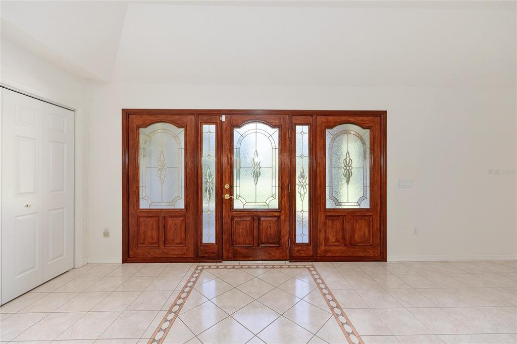 A foyer features a large wooden front door with glass panels and tiled flooring — 2657 W HAMPSHIRE STREET, INVERNESS, FL