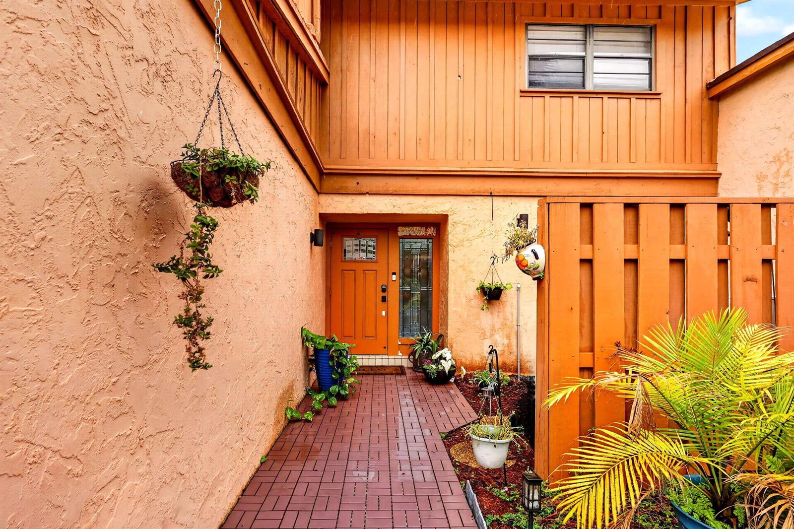 A brick walkway leads to an orange front door framed by stucco walls and wood siding — 5316 Stonybrook Lane, Boynton Beach FL 33437, BOYNTON BEACH, FL