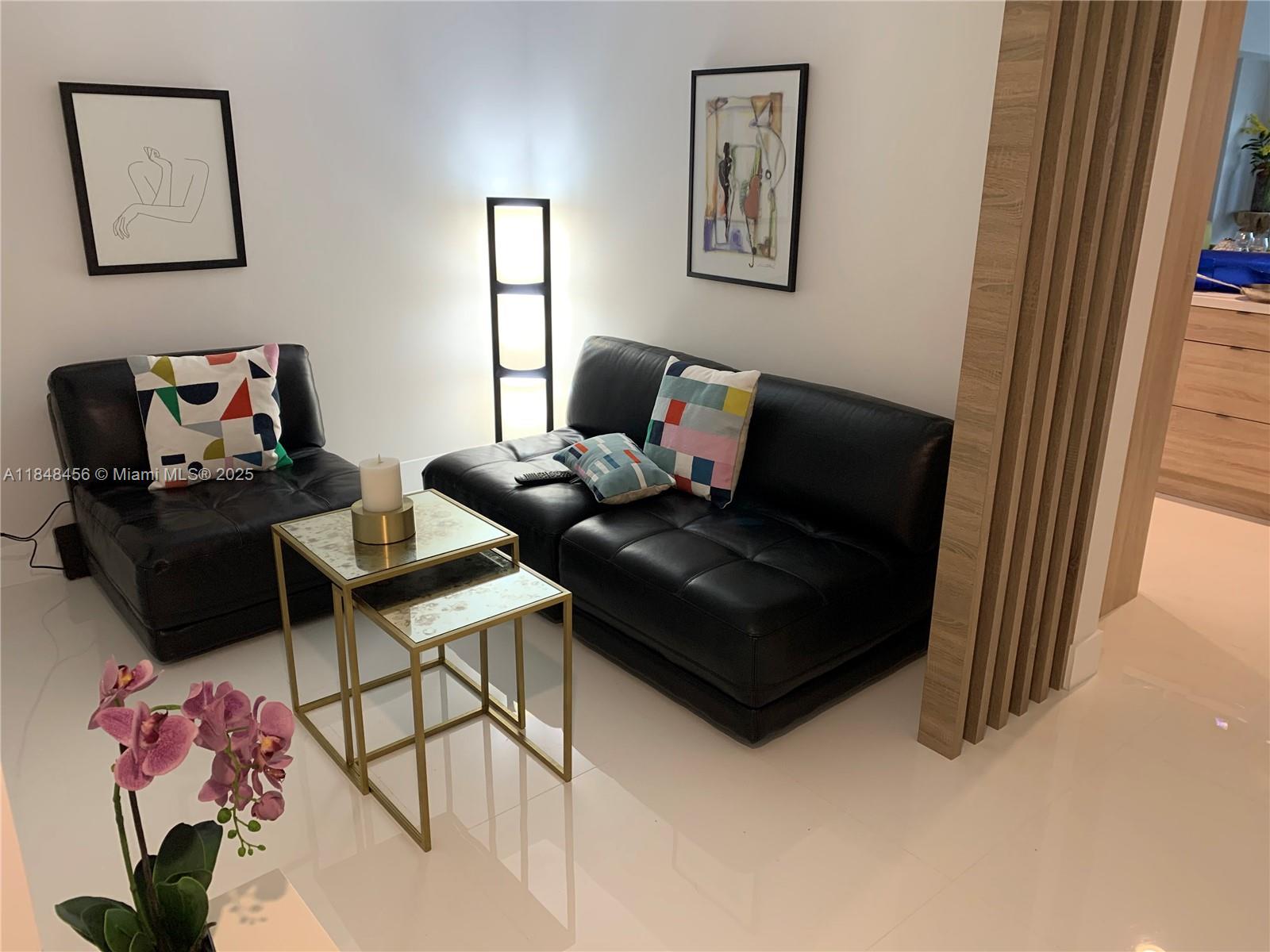 A living area features two black leather sofas, nesting tables, and wall art — 16385 Biscayne Blvd, North Miami Beach FL 33160, NORTH MIAMI BEACH, FL