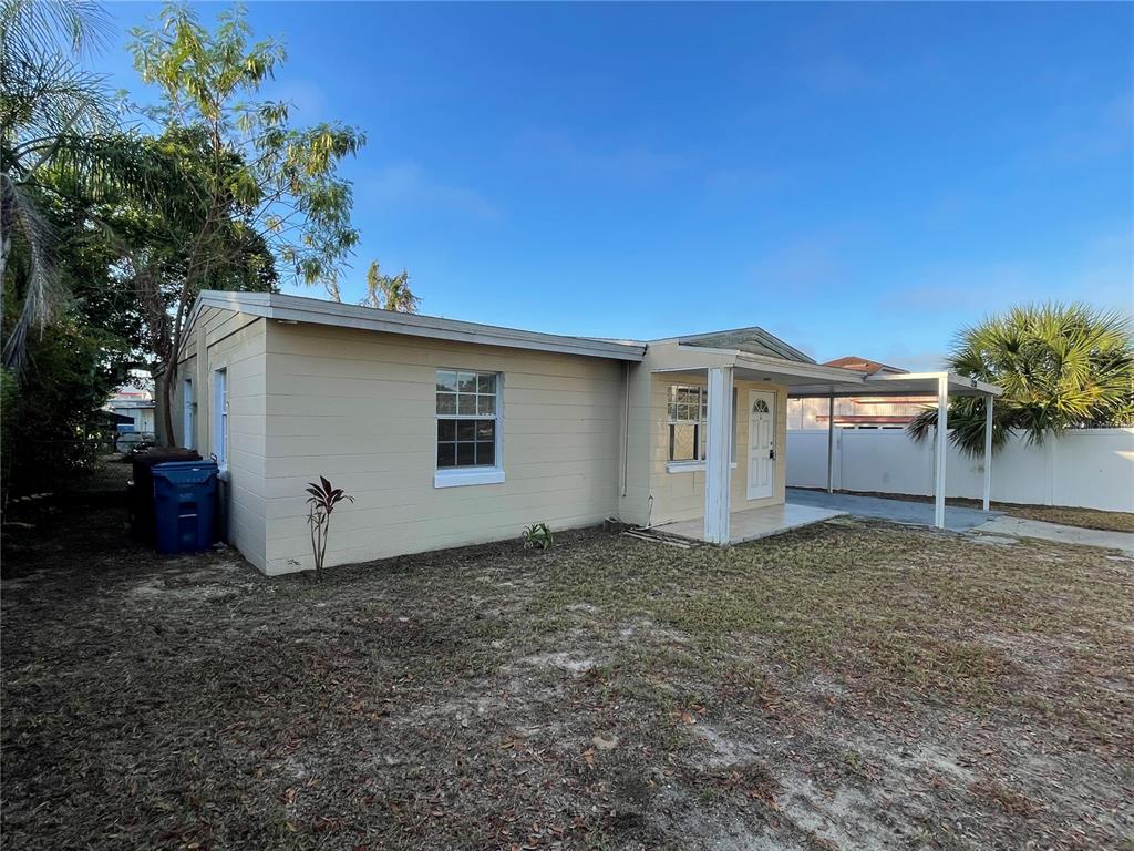 A single-story house with beige siding, a front porch, and an attached carport — 1208 CARLTON AVENUE, LAKE WALES, FL