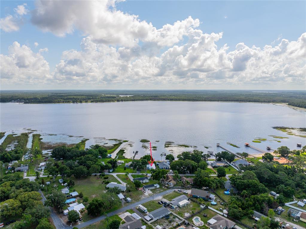 An aerial view shows a house with a red arrow pointing toward the waterfront property — 6125 LAKE LIZZIE DRIVE, ST CLOUD, FL
