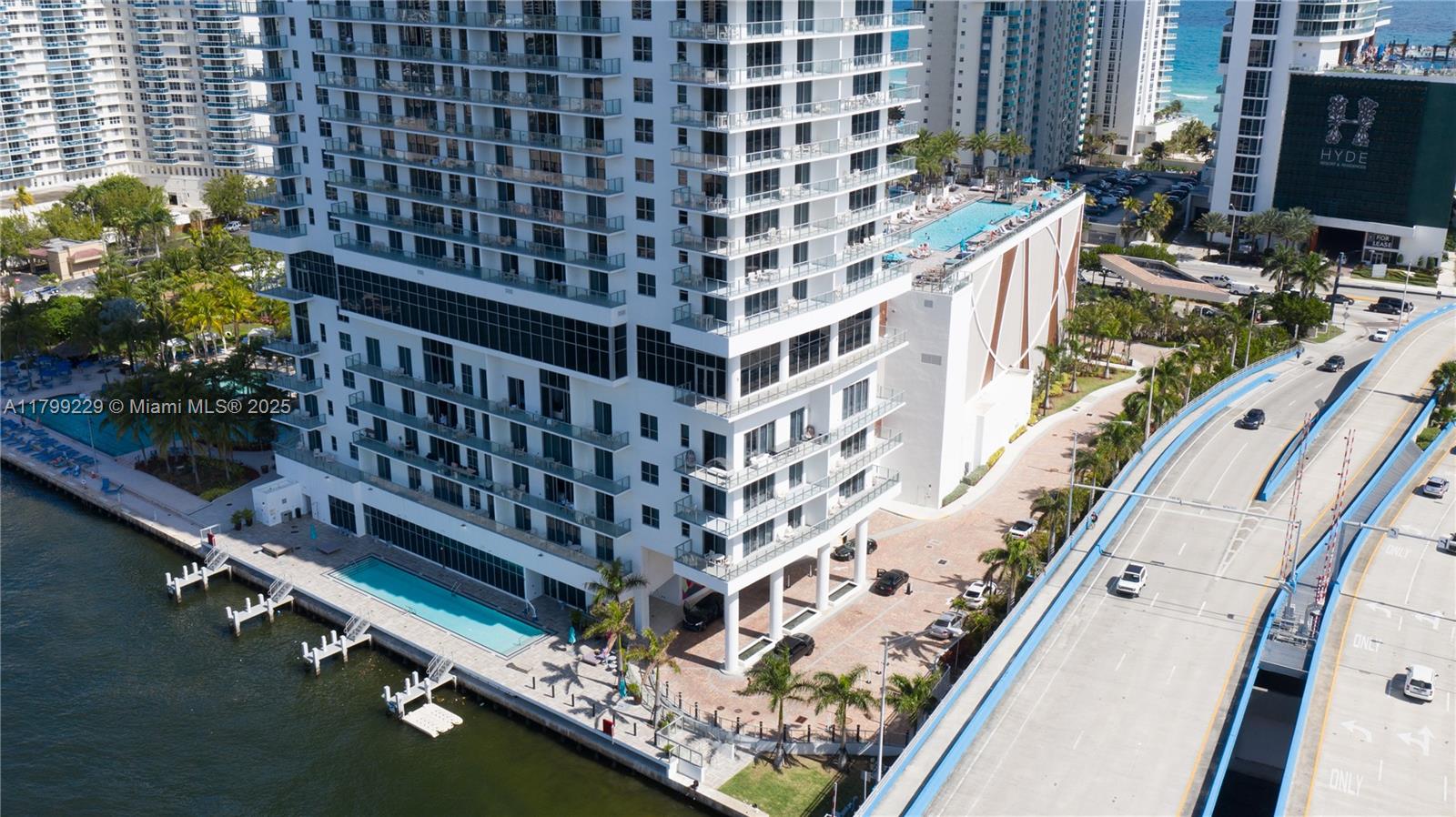 An aerial view shows a tall residential building with a waterfront pool and adjacent bridge — 4010 S Ocean Dr # 1, Hollywood FL 33019, HOLLYWOOD, FL