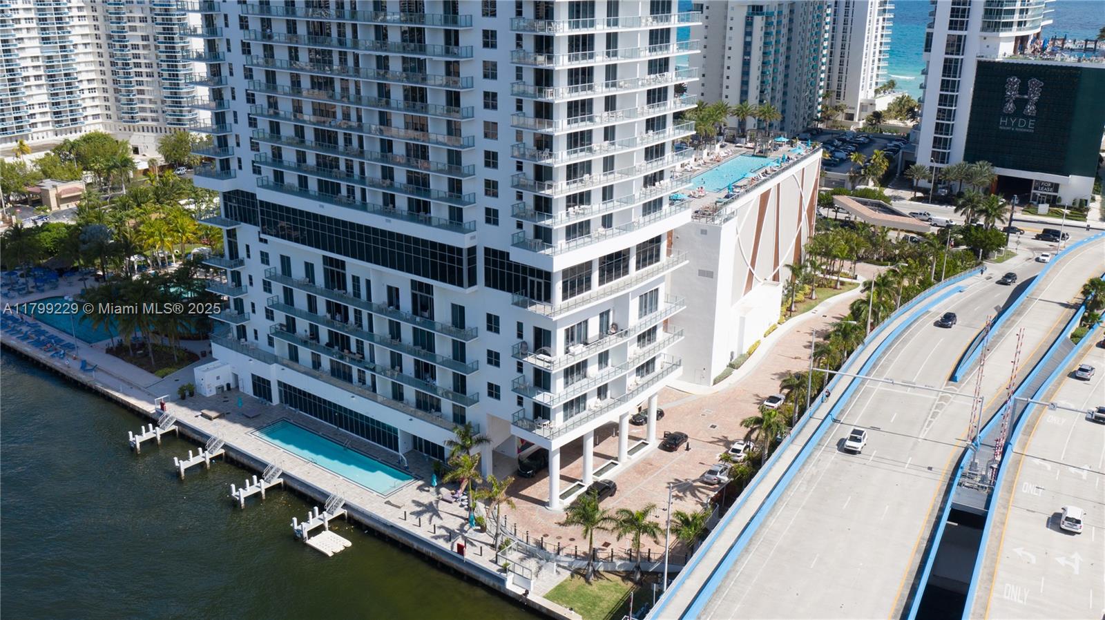 An aerial view shows a tall residential building with a waterfront pool and adjacent bridge — 4010 S Ocean Dr # 1, Hollywood FL 33019, HOLLYWOOD, FL