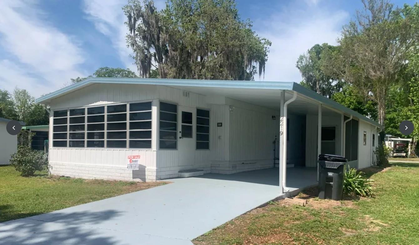 A single-story mobile home with a white exterior, a screened-in front porch, and a carport — 2219 NW 47th Circle, Ocala FL 34482, OCALA, FL