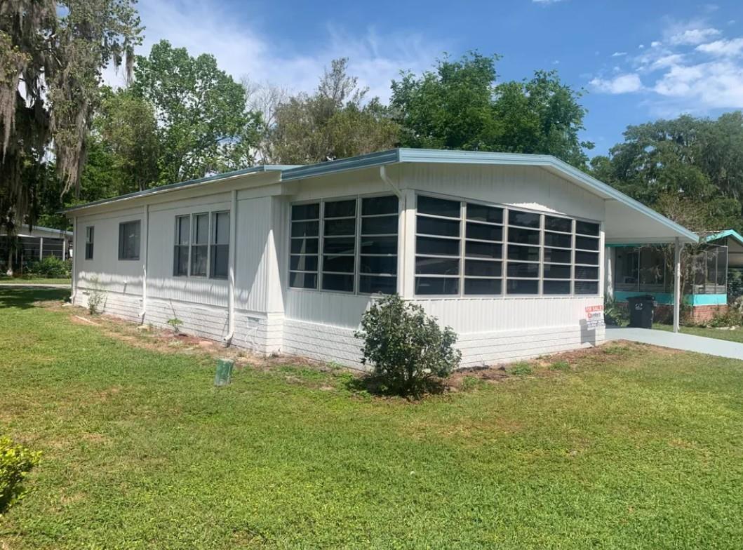 A white mobile home with a screened-in porch and a metal roof sits on grass — 2219 NW 47th Circle, Ocala FL 34482, OCALA, FL