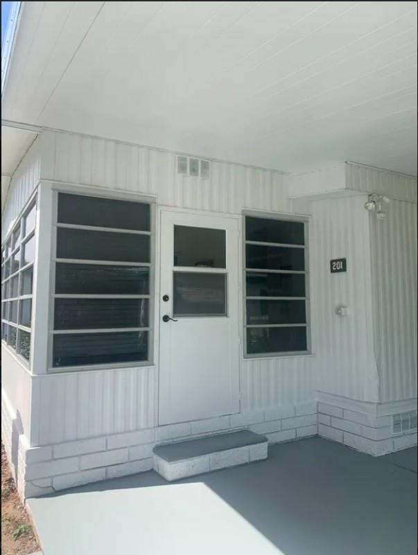 A white mobile home exterior features a front door, jalousie windows, and a concrete porch — 2219 NW 47th Circle, Ocala FL 34482, OCALA, FL