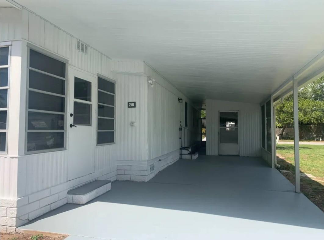 A white mobile home exterior features a gray painted carport and a covered concrete patio — 2219 NW 47th Circle, Ocala FL 34482, OCALA, FL