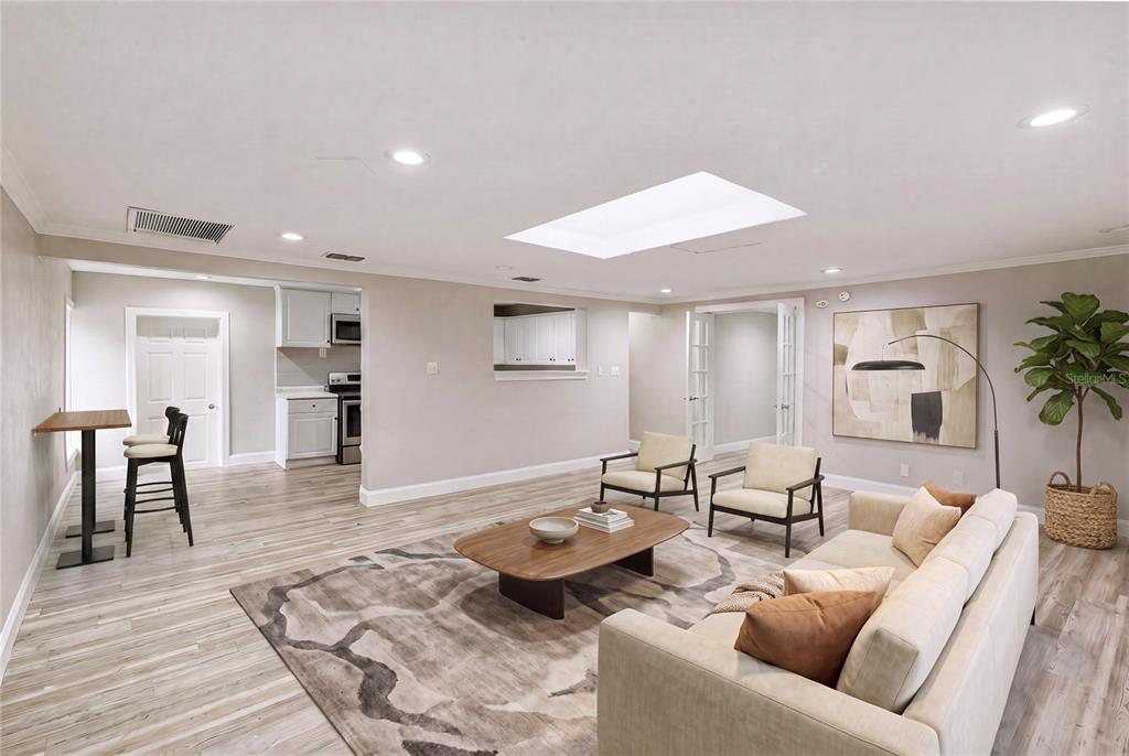 A living room with light wood-look flooring, a skylight, and an adjacent kitchen area — 1325 E LAURA STREET, PLANT CITY, FL
