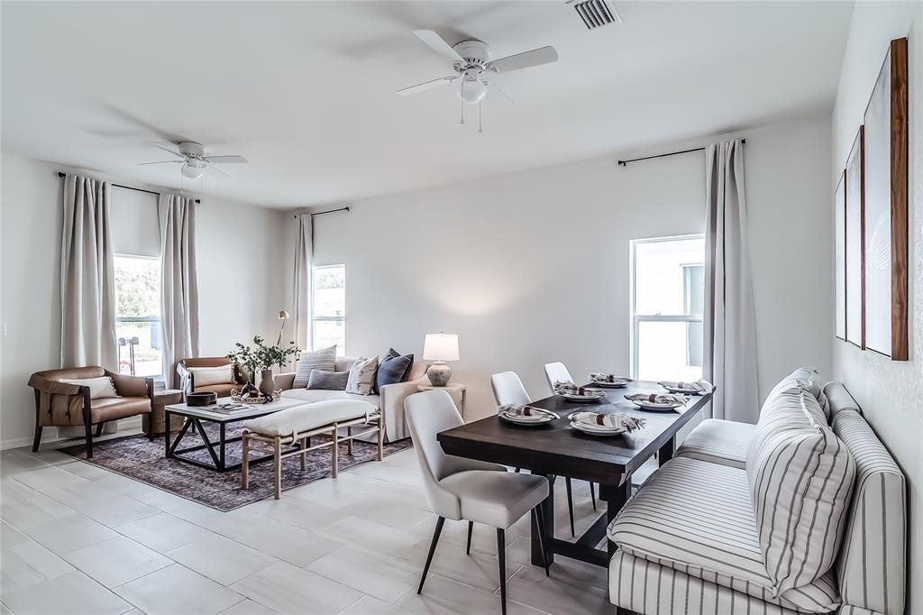 An open-concept living and dining area features light tile flooring, white walls, and ceiling fans — 1103 Gigon Court, Sebring FL 33870, SEBRING, FL