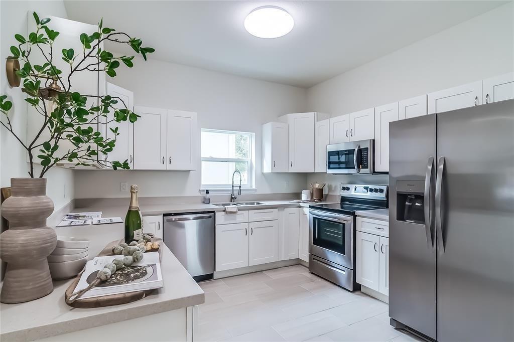 A kitchen features white cabinets, stainless steel appliances, and light-colored countertops and flooring — 1103 Gigon Court, Sebring FL 33870, SEBRING, FL