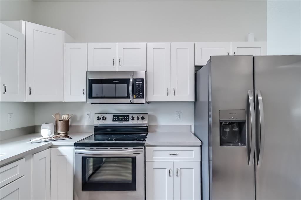 A kitchen features white cabinets, stainless steel appliances, and light gray countertops — 1103 Gigon Court, Sebring FL 33870, SEBRING, FL