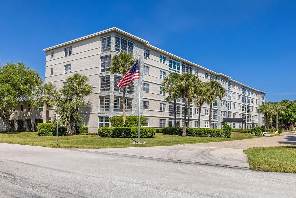 A multi-story apartment building with a light-colored facade stands behind a lawn and palm trees — 2333 Indian River Blvd # 306, Vero Beach FL 32960, VERO BEACH, FL