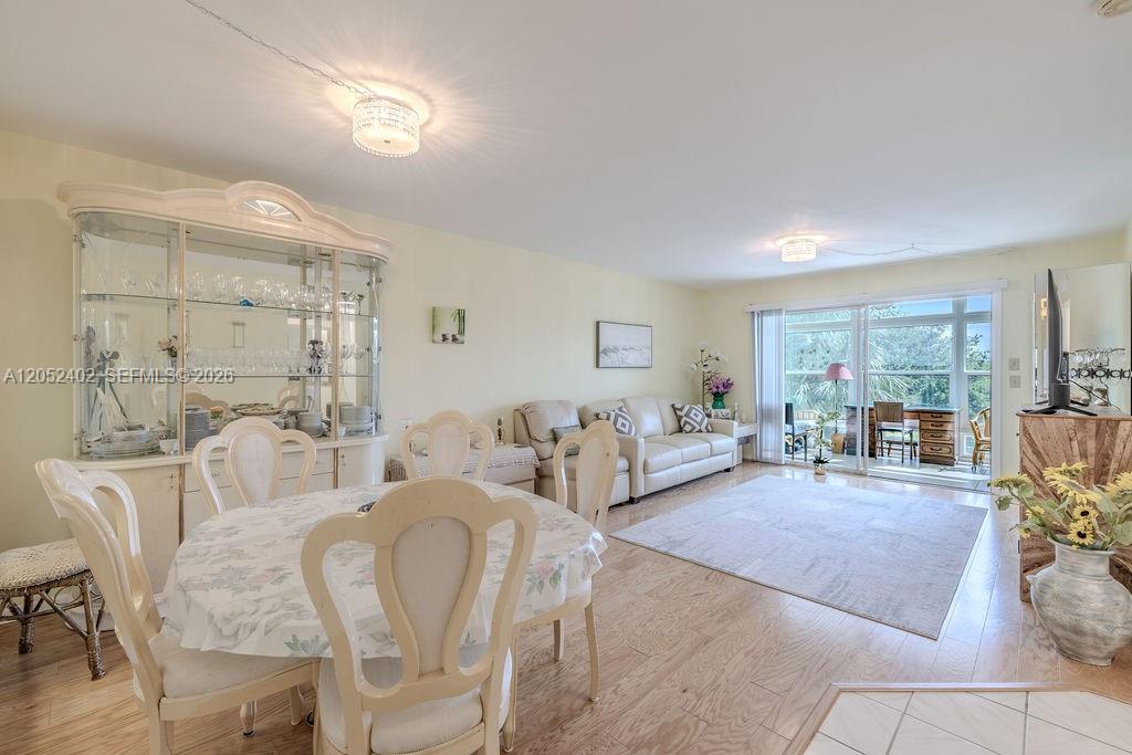 A dining area and living room with light wood floors, a china cabinet, and balcony — 2333 Indian River Blvd # 306, Vero Beach FL 32960, VERO BEACH, FL