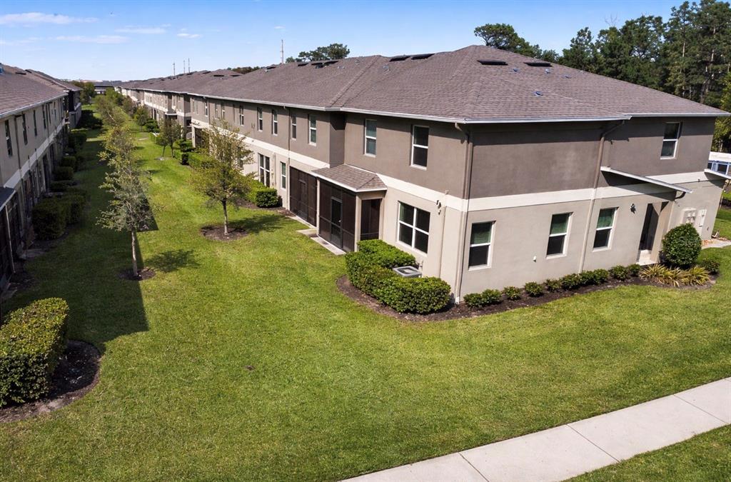 An aerial view shows the exterior of a multi-story apartment building with a grassy lawn — 15246 HARRINGTON COVE DRIVE, ORLANDO, FL