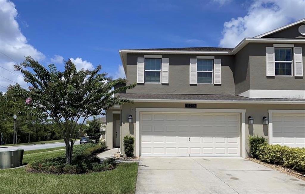 A two-story townhouse exterior features a beige facade, a white garage door, and a driveway — 15246 HARRINGTON COVE DRIVE, ORLANDO, FL