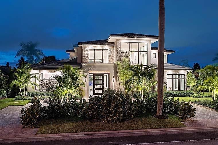 A modern two-story house with stone accents and palm trees is illuminated at dusk — 314 GRAVINA POINT, SANFORD, FL