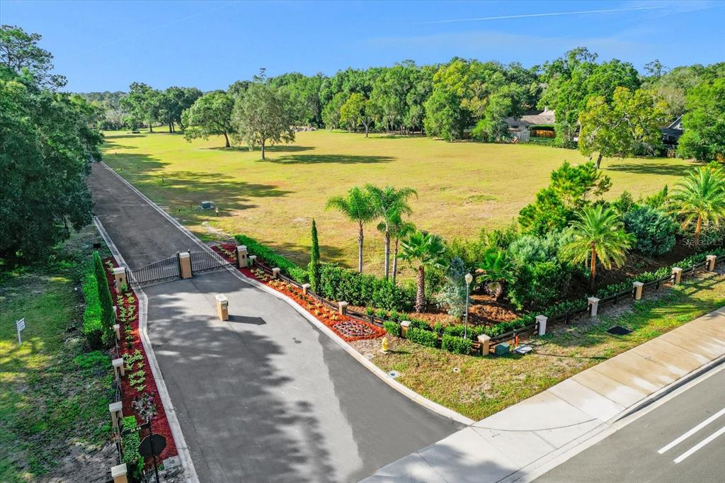 An aerial view shows a gated entrance leading to a large, grassy, undeveloped lot — 314 GRAVINA POINT, SANFORD, FL