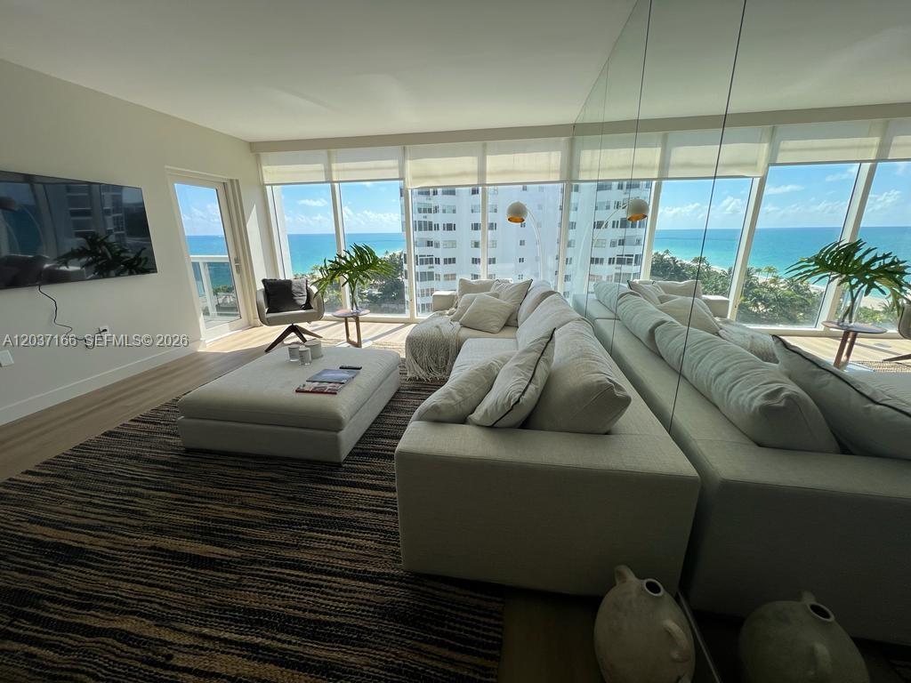 A living room features a large sectional sofa, an ottoman, and floor-to-ceiling ocean views — 10275 Collins Ave # 915, Bal Harbour FL 33154, BAL HARBOUR, FL