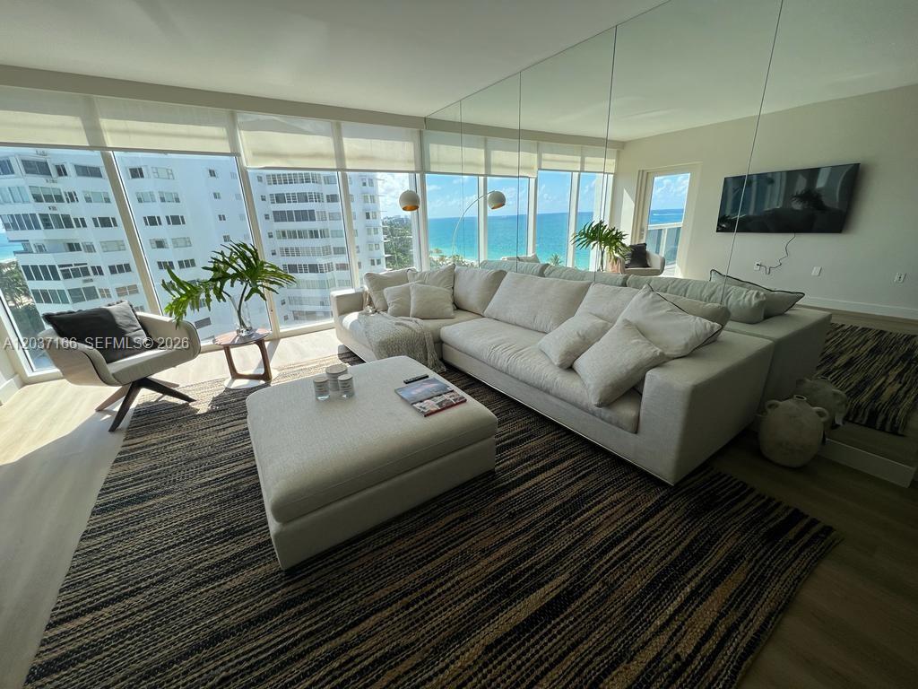 A living room features a large sectional sofa, an ottoman, and floor-to-ceiling ocean view windows — 10275 Collins Ave # 915, Bal Harbour FL 33154, BAL HARBOUR, FL