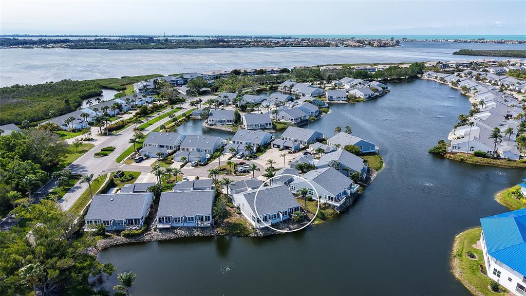 An aerial view shows a waterfront residential complex with a circled unit on the shore — 1005 PELICAN COURT, BRADENTON, FL
